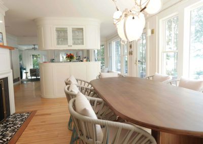large dining room table with fireplace to the left and kitchen in the background