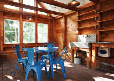 room with blue metal chairs and table to the left and stone sink to the right